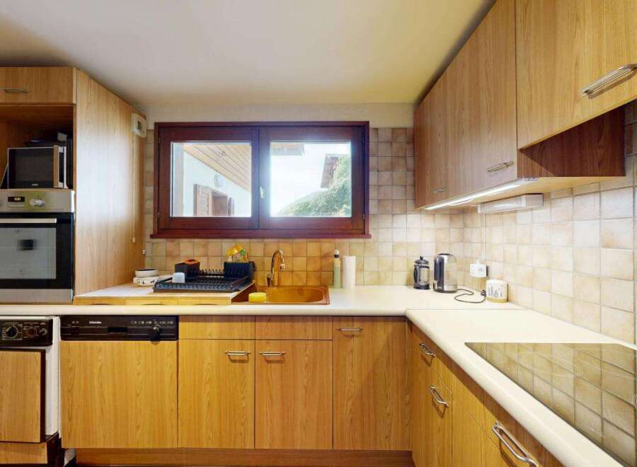 This charming kitchen features warm wood cabinetry and a tiled backsplash, creating a cozy and inviting atmosphere.