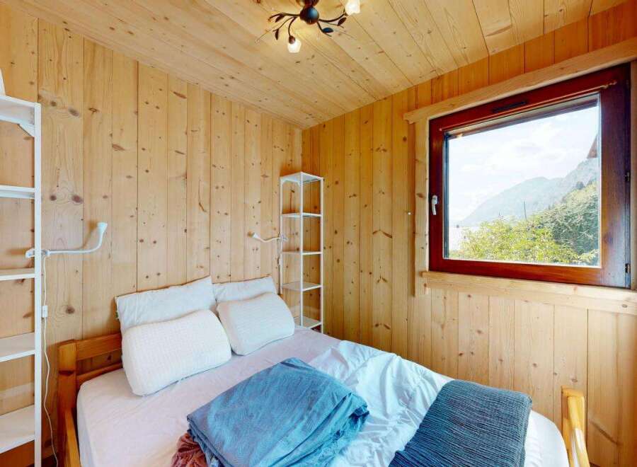 Experience cozy mountain living in this charming bedroom featuring warm wood paneling and a comfortable bed.