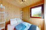 Experience cozy mountain living in this charming bedroom featuring warm wood paneling and a comfortable bed.
