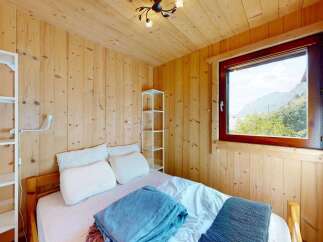 Experience cozy mountain living in this charming bedroom featuring warm wood paneling and a comfortable bed.