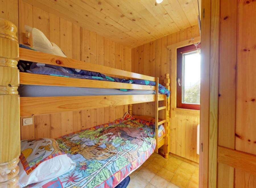 Discover cozy sleeping arrangements in this charming room, featuring a sturdy wooden bunk bed perfect for families or guests.