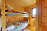 Discover cozy sleeping arrangements in this charming room, featuring a sturdy wooden bunk bed perfect for families or guests.