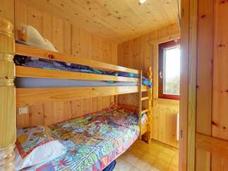 Discover cozy sleeping arrangements in this charming room, featuring a sturdy wooden bunk bed perfect for families or guests.