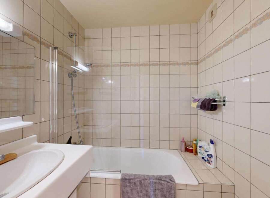 This bathroom features a clean and functional design with a bathtub and shower combination, perfect for relaxing after a long day.