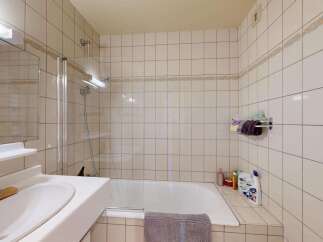 This bathroom features a clean and functional design with a bathtub and shower combination, perfect for relaxing after a long day.