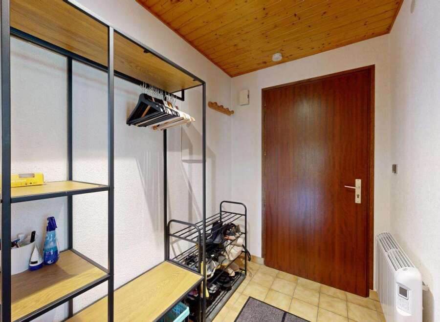 Welcome to this charming entryway, featuring a practical open shelving unit with ample space for shoes and coats.