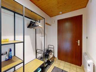 Welcome to this charming entryway, featuring a practical open shelving unit with ample space for shoes and coats.