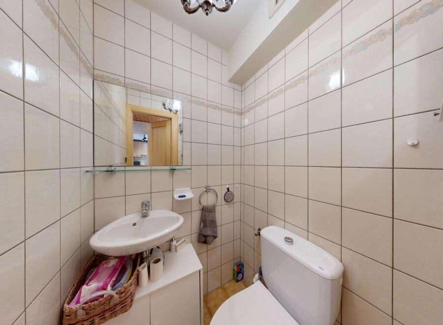 This bathroom features a compact vanity with a sink and a basket for storage, perfect for smaller spaces.