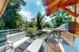 Enjoy breathtaking mountain views from this stunning wooden deck, complete with comfortable outdoor seating and a dining area.