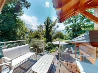 Enjoy breathtaking mountain views from this stunning wooden deck, complete with comfortable outdoor seating and a dining area.