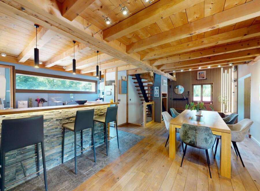 Experience rustic charm and modern comfort in this stunning open-plan living space, featuring a sleek kitchen island with stone accents and comfortable bar stools.