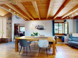 Experience rustic charm and modern comfort in this inviting dining area, featuring exposed wooden beams and a slatted wood accent wall.