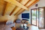 Experience rustic charm and modern comfort in this stunning attic living space, featuring exposed wooden beams and a cozy sectional sofa.