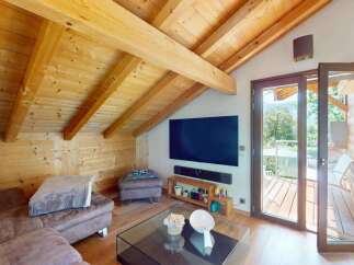 Experience rustic charm and modern comfort in this stunning attic living space, featuring exposed wooden beams and a cozy sectional sofa.