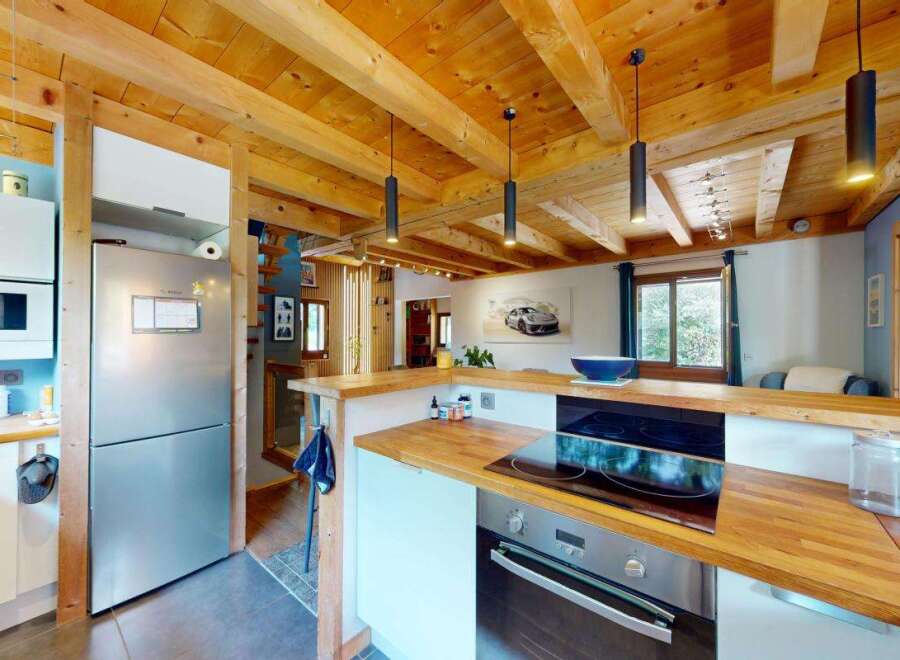 Experience rustic charm in this cozy kitchen featuring exposed wooden beams and a modern stainless steel refrigerator.