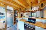 Experience rustic charm in this cozy kitchen featuring exposed wooden beams and a modern stainless steel refrigerator.