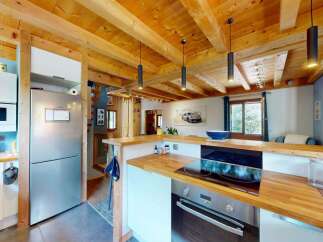 Experience rustic charm in this cozy kitchen featuring exposed wooden beams and a modern stainless steel refrigerator.