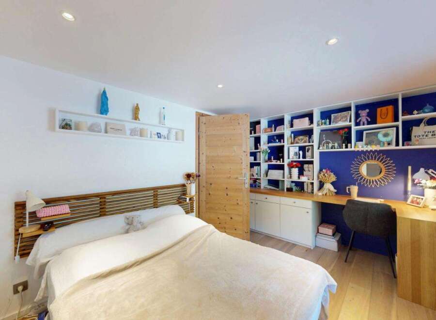 Discover this charming bedroom featuring a comfortable bed with a wooden headboard and a cozy blanket.