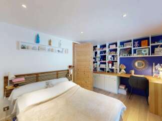 Discover this charming bedroom featuring a comfortable bed with a wooden headboard and a cozy blanket.