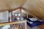 Discover this charming attic space, featuring a cozy sleeping area with a plush bed and a comfortable seating area with a dark blue sofa adorned with patterned pillows.