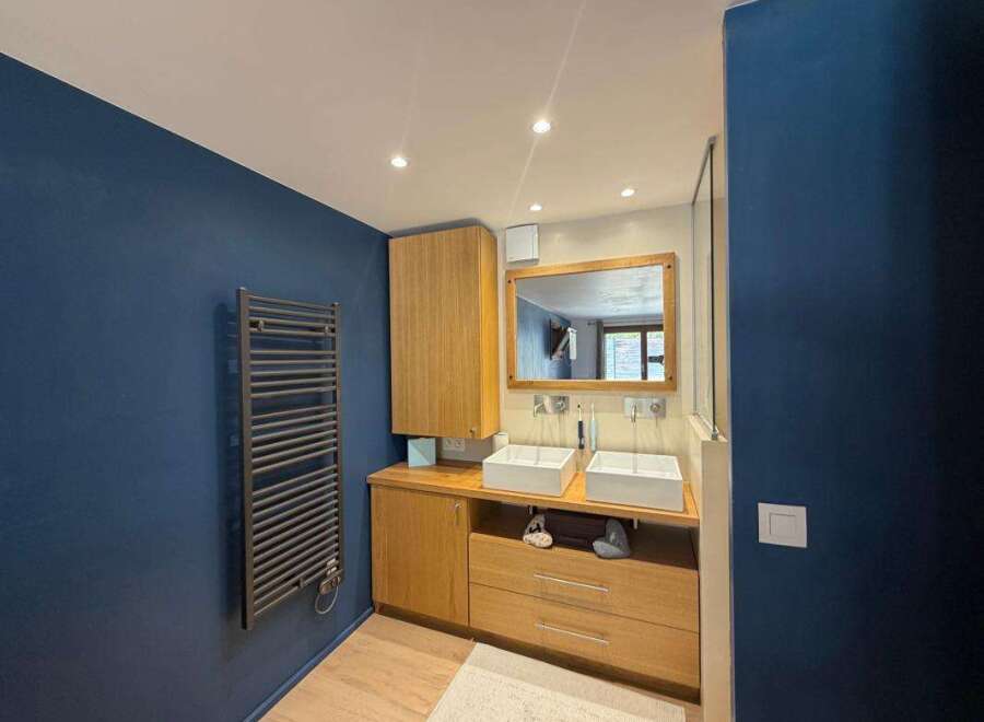 This modern bathroom features a sleek design with a double vanity, complete with two square vessel sinks and modern faucets.