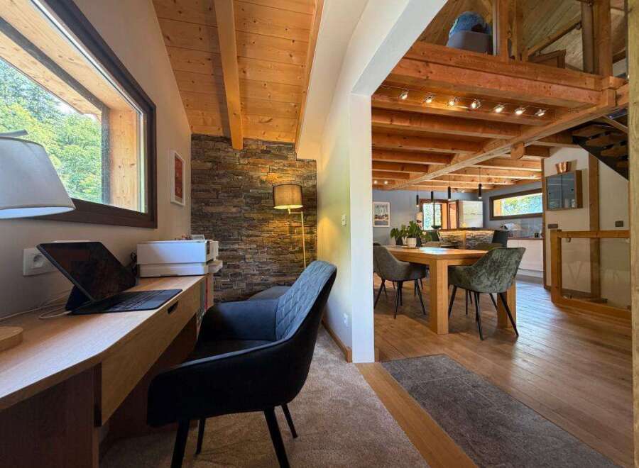 This charming home features a dedicated workspace with a large window offering scenic views and a comfortable desk setup.