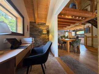 This charming home features a dedicated workspace with a large window offering scenic views and a comfortable desk setup.