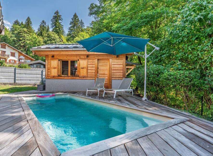 Escape to this serene backyard oasis featuring a sparkling swimming pool surrounded by a spacious wooden deck.
