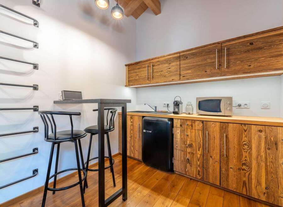 This charming studio apartment features a compact kitchenette with rustic wooden cabinetry, a mini-fridge, and a microwave, perfect for preparing simple meals.