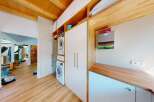 Discover a modern laundry room featuring stacked washer and dryer units, ample storage with white cabinets, and a sleek wooden countertop.