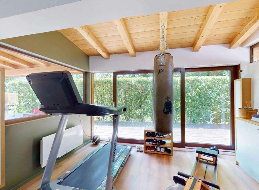 This home gym features a spacious workout area with a treadmill, punching bag, and rowing machine, perfect for a comprehensive fitness routine.