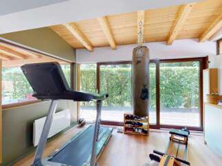 This home gym features a spacious workout area with a treadmill, punching bag, and rowing machine, perfect for a comprehensive fitness routine.