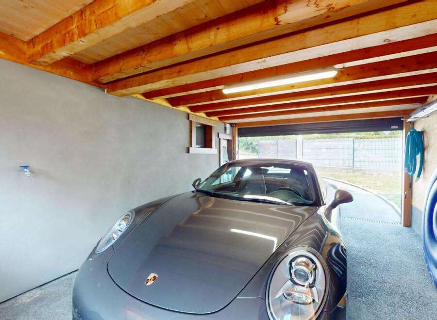 This spacious garage offers ample parking for your vehicles, featuring a sleek grey Porsche.