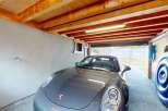 This spacious garage offers ample parking for your vehicles, featuring a sleek grey Porsche.