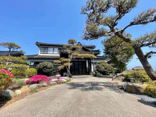 Discover this charming Japanese-style home featuring a traditional tiled roof and elegant dark wood doors.