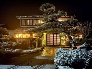 Experience the magic of winter with this enchanting property, beautifully illuminated by festive lights against a snowy backdrop.