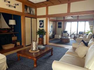 Experience serene living in this beautifully appointed Japanese-style room, featuring a spacious living area with comfortable white sofas and a traditional low wooden coffee table.