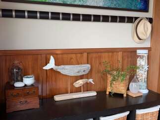 Coastal-inspired decor enhances this entryway, featuring a driftwood whale sculpture and a glass jar filled with seashells.
