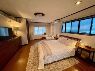 Experience breathtaking ocean views from this serene bedroom, featuring a comfortable bed and a cozy seating area.
