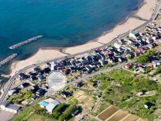 Discover coastal living with this stunning aerial view of a property nestled between the serene blue ocean and a charming residential area.