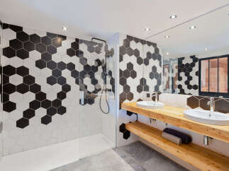 Experience modern luxury in this stunning bathroom featuring a striking black and white hexagonal tile design that extends from the walls to the shower enclosure.