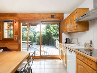 Experience seamless indoor-outdoor living in this charming kitchen and dining area, featuring a large sliding glass door that opens onto a spacious wooden deck.