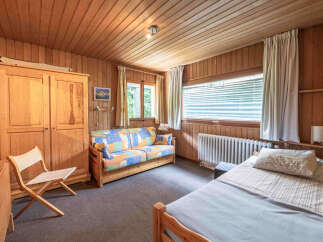 This charming room features a cozy wooden interior with a comfortable sofa bed and a single bed, perfect for accommodating guests.