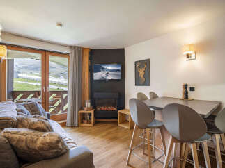Experience cozy mountain living in this charming apartment featuring a modern electric fireplace and a spacious dining area perfect for family meals.