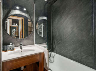 Experience modern luxury in this stylish bathroom featuring a sleek vanity with a white basin and a dark wood cabinet.