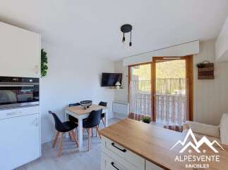 This charming apartment features a modern kitchen with integrated appliances, a cozy dining area perfect for intimate meals, and a bright living space with access to a balcony offering scenic mountain views.
