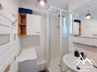 Discover this charming bathroom featuring a modern shower cabin and a convenient washing machine.