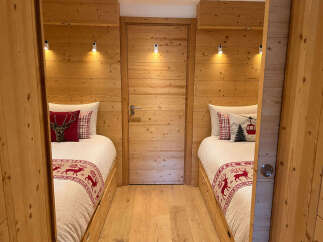 Experience cozy mountain living in this charming room featuring two twin beds adorned with festive deer and ski-themed pillows.