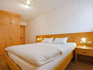 Experience rustic charm in this cozy bedroom featuring a spacious wooden bed with crisp white linens and a plush duvet.