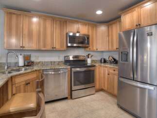 This spacious kitchen features beautiful light wood cabinetry and granite countertops, offering ample storage and a timeless aesthetic.